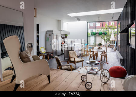 Moderna cucina a pianta aperta spazio soggiorno con poltrona e il triciclo in primo piano. Foto Stock