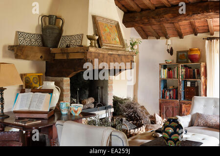 Gran legno e pietra caminetto in soggiorno con soffitto a travi e armadio invecchiato Foto Stock