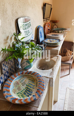 Dipinto a mano le piastre sulla cucina piastrellata ledge con lavello in pietra e vintage segno dello smalto Foto Stock