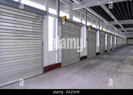 Una lunga fila di rullo di chiusura porte in un magazzino Foto Stock