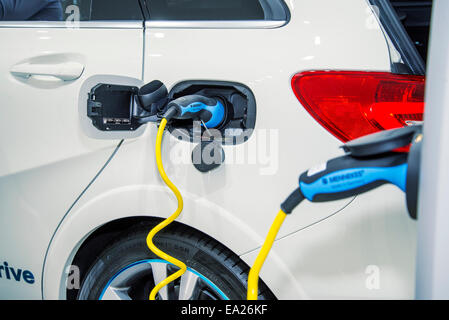 Auto elettrica essendo caricato in corrispondenza di una stazione di carico. Foto Stock