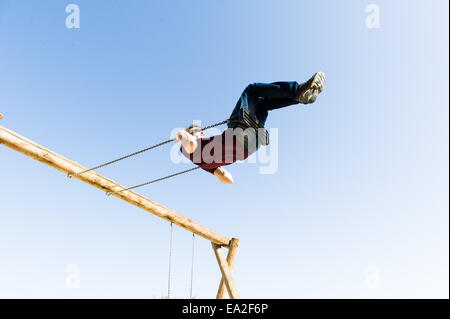 Una figura oscilla su un parco giochi swing. Foto Stock