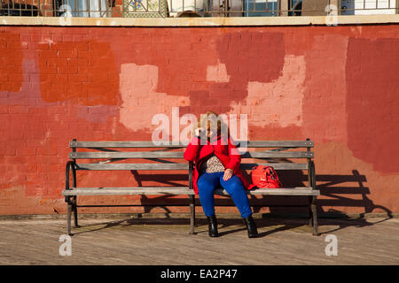 Una donna seduta sul lungomare, la spiaggia di Brighton Brooklyn, New York, Stati Uniti d'America Foto Stock