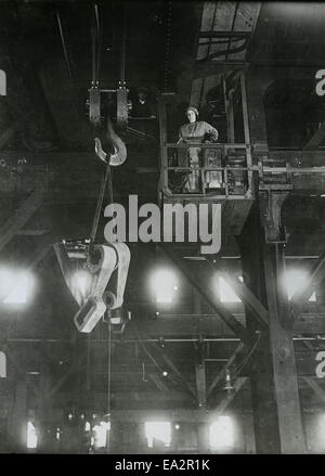 Una fotografia di una donna che gestisce una gru O.E.T. che mostra il ruolo delle donne nei settori industriale ed edile. L'immagine evidenzia l'abilità e la precisione necessarie per il funzionamento con gru in ambienti gravosi. Foto Stock