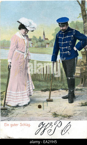 Questa cartolina d'epoca presenta una coppia che gioca a croquet in un piacevole ambiente all'aperto, catturando un momento di attivita' sociale e divertimento tipico dell'inizio del XX secolo. La scena evidenzia la popolarità del croquet come sport ricreativo in quell'epoca. Foto Stock