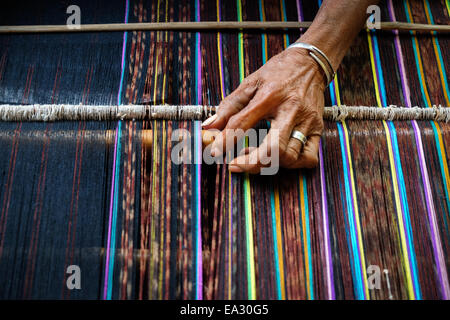 La mano di una donna vecchia tessitura di tessuti tradizionali chiamati ikat mostrando presso il proprio laboratorio nel villaggio Lamagute, Lembata, Indonesia. Foto Stock