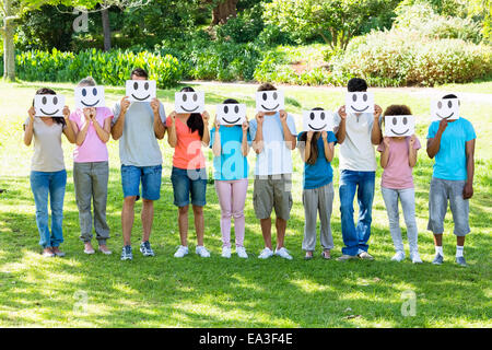 Amici multietnica holding smiley in posizione di parcheggio Foto Stock