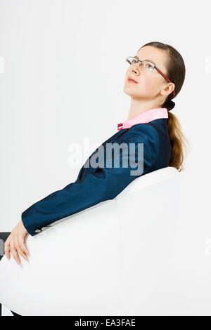 La donna in una giacca blu e i bicchieri si siede Foto Stock