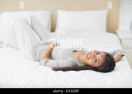 Ragazza giovane sdraiato sul letto guardando la fotocamera Foto Stock