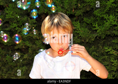 Giovane ragazzo giocando con bolle in giardino Foto Stock