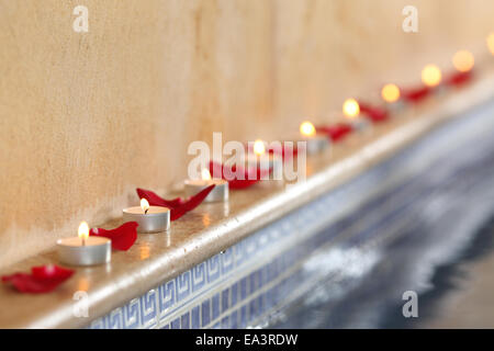 Close up di candele accese e petali di rosa in una spa romantica a bordo piscina e relax concept Foto Stock