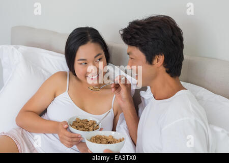 Felice coppia avente la colazione a letto Foto Stock