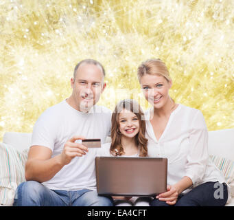 La famiglia felice con computer portatile e una carta di credito Foto Stock