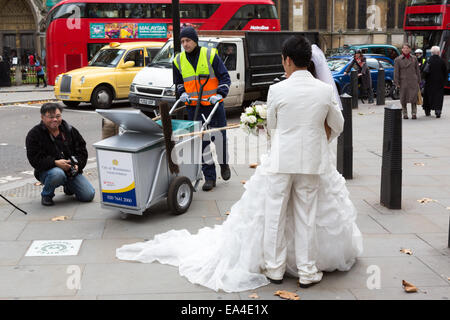 Un consiglio street sweeper da Westminster Consiglio passeggiate attraverso un cinese wedding photo shoot a Londra Foto Stock