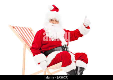 Santa dando un pollice in alto seduto in una sedia a sdraio isolati su sfondo bianco Foto Stock