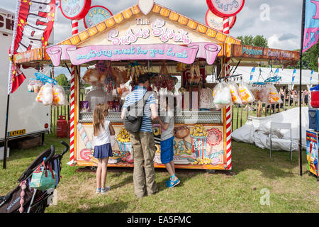 L'uomo comprare dolci per i bambini da una bancarella vendendo zuccherino di spuntini in un inglese estate fiera. Foto Stock