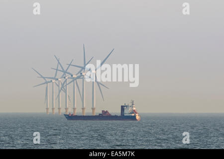 Energia eolica turbine e barge in mare vicino a Clacton-on-Sea, Essex, Inghilterra, in opaco alla luce della sera. Foto Stock