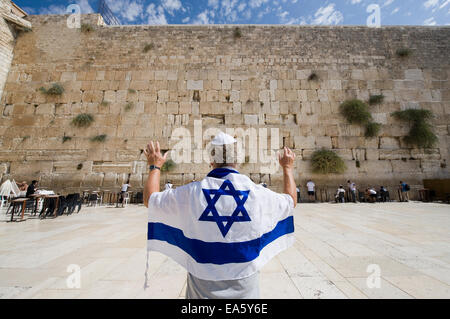 Un uomo con un Israelian bandiera e le sue braccia sollevate nella parte anteriore del western il muro del pianto per la città vecchia di Gerusalemme Foto Stock