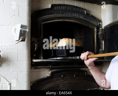 Pane appena sfornato che viene rimosso da un tradizionale vecchio forno da un panettiere locale. Foto Stock