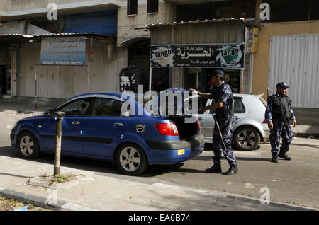 Rafah nella striscia di Gaza, Territori palestinesi. 7 Nov, 2014. Un membro delle forze di sicurezza palestinesi ispeziona un auto durante un giro di vite dopo una serie di esplosioni di coordinate sono state indirizzate le case di diversi leader del Presidente Mahmoud Abbas' Fatah partito, a Rafah nel sud della striscia di Gaza, 7 novembre 2014. Almeno dieci esplosioni ha colpito le case e le autovetture appartenenti a membri del movimento Fatah nella Striscia di Gaza il venerdì, testimoni di detto credito: Abed Rahim Khatib/immagini APA/ZUMA filo/Alamy Live News Foto Stock