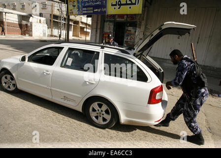 Rafah nella striscia di Gaza, Territori palestinesi. 7 Nov, 2014. Un membro delle forze di sicurezza palestinesi ispeziona un auto durante un giro di vite dopo una serie di esplosioni di coordinate sono state indirizzate le case di diversi leader del Presidente Mahmoud Abbas' Fatah partito, a Rafah nel sud della striscia di Gaza, 7 novembre 2014. Almeno dieci esplosioni ha colpito le case e le autovetture appartenenti a membri del movimento Fatah nella Striscia di Gaza il venerdì, testimoni di detto credito: Abed Rahim Khatib/immagini APA/ZUMA filo/Alamy Live News Foto Stock