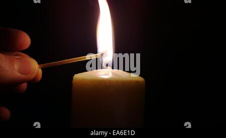 Uomo che illumina una candela con una partita Foto Stock