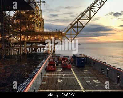 Imbarcazione nautica che si avvicina a una piattaforma petrolifera all'alba Foto Stock