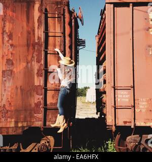 Cowgirl che arrampica un treno abbandonato Foto Stock