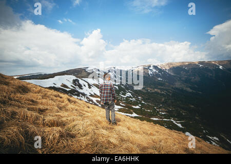 Giovane uomo in piedi in campo e cercando di visualizzare Foto Stock