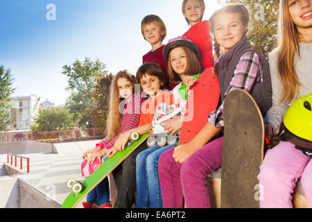 Bambini sorridenti con skateboard sedersi insieme Foto Stock