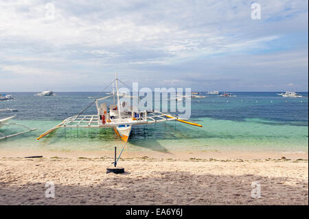 Un immersioni completamente attrezzato outrigger imbarcazione a vela è ancorato alla struttura Alona Beach in Panglao Island, Bohol, isole filippine. Foto Stock