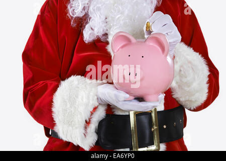 Close Up di Babbo Natale mettendo moneta nel salvadanaio Foto Stock