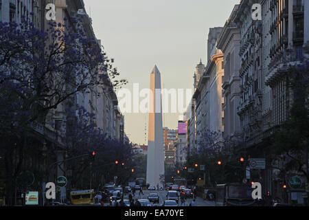 L'obelisco di Buenos Aires al tramonto in primavera, con alberi di Jacaranda in fiore su 'Diagonal Norte'. Argentina. Foto Stock