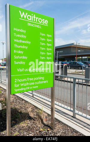 Firmare all'entrata di un supermarket Waitrose parcheggio auto elencando gli orari di apertura del negozio. Foto Stock