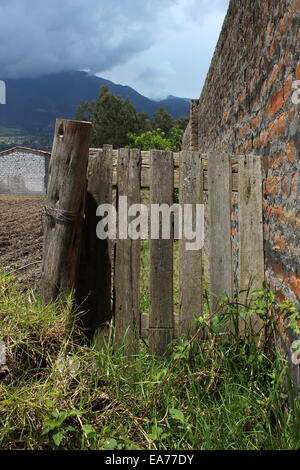 Un cancello di legno accanto a un muro di mattoni di adobe in Cotacachi, Ecuador Foto Stock