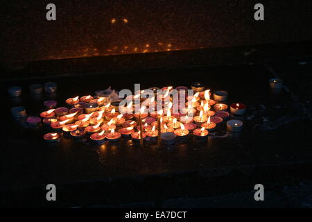 Il gruppo accesa memorial candele nel buio con la riflessione in pietra Foto Stock