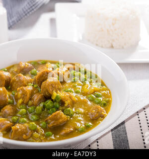 Grande ciotola di salsa speziata salsicce con piselli e un lato di riso Foto Stock