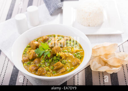 Grande ciotola di salsa speziata salsicce con piselli e un lato del riso e papadum Foto Stock