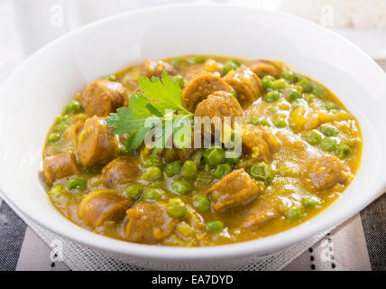 Grande ciotola di salsa speziata salsicce con piselli e un lato di riso Foto Stock