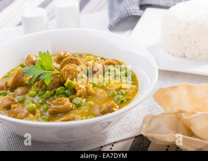 Grande ciotola di salsa speziata salsicce con piselli e un lato del riso e papadum Foto Stock