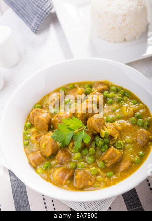 Grande ciotola di salsa speziata salsicce con piselli e un lato di riso Foto Stock