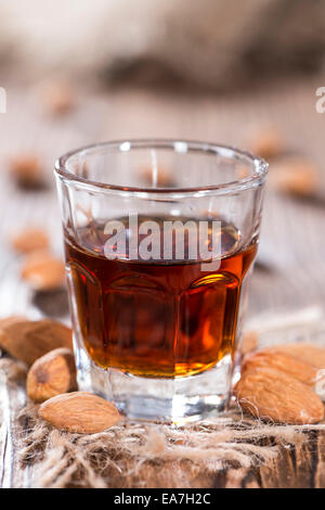 Amaretto Shot sul legno scuro dello sfondo con alcune mandorle Foto Stock