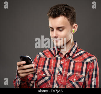 Caucasian ragazzo adolescente ascoltando la musica a cuffie dal suo smartphone Foto Stock