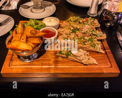 Il granchio e avocado Crostini con insalata e patatine fritte, presentato su una tavola di legno, a pranzo il cielo. Foto Stock
