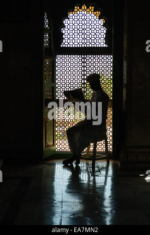 Uomo che legge il giornale in parte anteriore del vetro in silhouette, Jaswant Thada, Jodhpur, Rajasthan, India Foto Stock