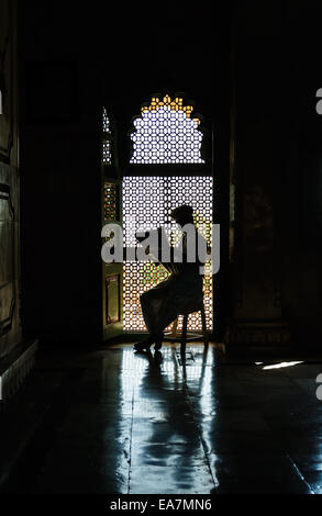 Uomo che legge il giornale in parte anteriore del vetro in silhouette, Jaswant Thada, Jodhpur, Rajasthan, India Foto Stock