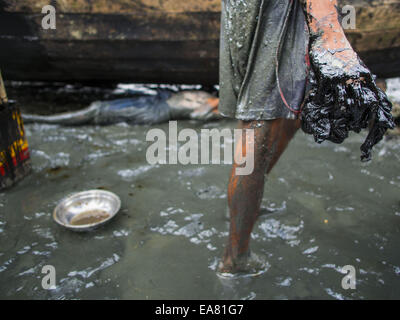 Sittwe, Rakhine, Myanmar. 7 Nov, 2014. Un lavoratore con le mani in mano, coperto di catrame, nei pressi di una barca che sta lavorando nel porto di un IDP camp per i Rohingya musulmani nei pressi di Sittwe. Il governo del Myanmar ha costretto più di 140.000 Rohingya musulmani che vivevano in Sittwe, Myanmar, nella squallida sfollati interni Persona (IDP) campi. Il trasferimento forzato ha avuto luogo nel 2012 dopo la violenza settaria devastato Rohingya europee di Sittwe e ha lasciato centinaia di morti. Nessuno dei campi hanno elettricità e alcuni hanno negato accesso a regolari di razioni alimentari per nove mesi. Condizioni per i Rohingya in ca Foto Stock