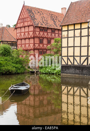 Metà case con travi di legno del vecchio Aarhus. Una piccola barca a remi è ancorata in acqua calma di fronte danese tradizionale case di fiume Foto Stock