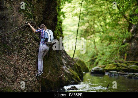 Giovane donna escursionista arrampicata su cavi di sicurezza in un burrone sopra il fiume Foto Stock