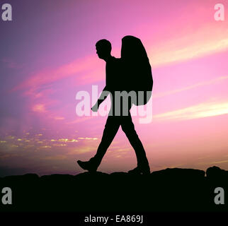 Escursionista con zaino contro un tramonto viola Foto Stock